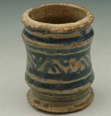 This small ceramic jar would have been used to store medicine like ointments, salves, or powders. It could have belonged to a household, or to a professional apothecary. Surgeons and physicians tended to the sick, but apothecaries made and sold medication. Many people working in the medical professions were middling in status. Either educated at school or university (physicians) or through an apprenticeship (surgeons and physicians), a significant amount of learning and knowledge was required to treat the sick. To become an apothecary, you had to train for roughly seven years, as was the case for many trade and craft apprenticeships. This kind of learned skill, honed through books as well as practical engagement, was a feature of new professional middling identities. <br />
<br />
Port towns like Bristol, with excellent trade links to the rest of the world for raw materials, boasted several apothecaries  for instance Richard Woodson of St Thomas parish in Bristol left Instruments of silver and trimmed with silver worth 3 18s 4d, with all his other Instruments of all sorts worth 50s and all his books belonging to Chururgery at 30s, when he died in 1623.  In the same town in 1642, Richard Brace, Gent and Practioner in the Art of Phisique had a still house for distilling medicinal waters, and owned silver instruments, chests of glass bottles, boxes of cordials, chemical oils, chemical salts, other tools including lances, syringes and a pair of scissors, and one Frame of Gallipotts like the one above. In addition to 120 books in his study (6), he also kept Gerrards Herball and Romulinus his Anotomie with his equipment, priced separately (30 and 8s respectively).<br />
<br />
Many of the treatments prescribed to patients were natural remedies like herbs or animal products. This meant that households often had their own ointment jars filled with salves and balms to help against all manner of illnesses and injuries. Drug jars ranged in sizes and decoration depending on their use. Those owned by the professional apothecaries could be very elaborate indeed. Often imported from Italy, the most fashionable vessels were the brightly decorated majolica jars from Venice. Most people of middling status would have been familiar with these jars, either from their own supply of medicine, or through the medication provided by an apothecary.